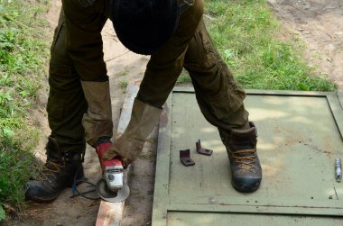 Dışarıdaki çelik yapıda elektrikli tekerlek gıcırdıyor. Koruyucu eldivenli eski bir işçi metal kapıyı öğütücüyle kesiyor. Demir öğütürken kıvılcımlar