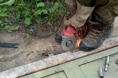 Dışarıdaki çelik yapıda elektrikli tekerlek gıcırdıyor. Koruyucu eldivenli eski bir işçi metal kapıyı öğütücüyle kesiyor. Demir öğütürken kıvılcımlar