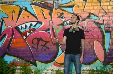 Boynunda gaz maskesi olan genç bir grafiti sanatçısı sprey kutusunu renkli pembe duvar yazısına fırlatıyor. Sokak sanatı ve çağdaş boyama süreci. Gençlik alt kültüründe eğlence