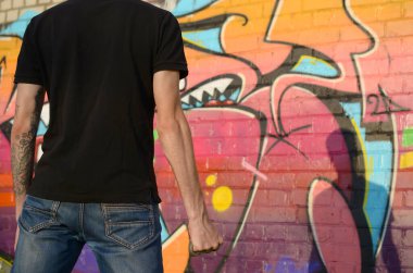 Elinde pirinçle kenar mahalle tuğlasından duvarlar ve grafiti tabloları olan beyaz bir genç adam. Suç gücü kavramı ve saldırganlık suçlaması. Klasik gangster kavgası silahı.
