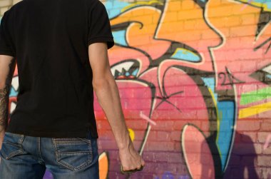 Elinde pirinçle kenar mahalle tuğlasından duvarlar ve grafiti tabloları olan beyaz bir genç adam. Suç gücü kavramı ve saldırganlık suçlaması. Klasik gangster kavgası silahı.