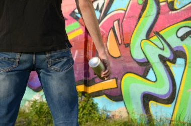 Sırt çantası ve gaz maskesi takan genç grafiti sanatçısı, tuğla duvara pembe tonlarda grafiti yapıyor. Sokak sanatı ve çağdaş boyama süreci. Gençlik alt kültüründe eğlence