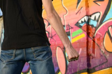 Elinde pirinçle kenar mahalle tuğlasından duvarlar ve grafiti tabloları olan beyaz bir genç adam. Suç gücü kavramı ve saldırganlık suçlaması. Klasik gangster kavgası silahı.