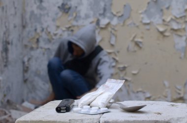 Umutsuzluk içindeki genç adam eroin paketleri ve uyuşturucu haplarının yanında narkotik etkilerden muzdarip. Uyuşturucu bağımlılığı ve yasadışı uyuşturucu kaçakçılığı sorunları