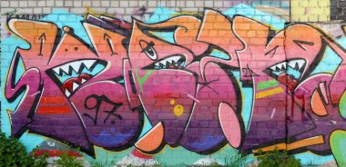 Eski tuğla duvardaki graffiti resimlerinin soyut renkli bir parçası. Yazılmamış mektupların ve renkli lekelerin olduğu sokak sanatı kompozisyonu. Kırmızı renklerde alt kültür arkaplan dokusu