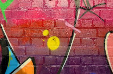 Eski tuğla duvardaki graffiti resimlerinin soyut renkli bir parçası. Yazılmamış mektupların ve renkli lekelerin olduğu sokak sanatı kompozisyonu. Kırmızı renklerde alt kültür arkaplan dokusu