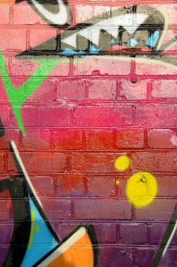 Eski tuğla duvardaki graffiti resimlerinin soyut renkli bir parçası. Yazılmamış mektupların ve renkli lekelerin olduğu sokak sanatı kompozisyonu. Kırmızı renklerde alt kültür arkaplan dokusu