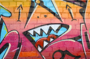 Eski tuğla duvardaki graffiti resimlerinin soyut renkli bir parçası. Yazılmamış mektupların ve renkli lekelerin olduğu sokak sanatı kompozisyonu. Kırmızı renklerde alt kültür arkaplan dokusu