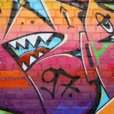 Eski tuğla duvardaki graffiti resimlerinin soyut renkli bir parçası. Vahşi harfler ve renkli lekelerle dolu sokak sanatı kompozisyonu. Sıcak renklerde alt kültür arkaplan dokusu