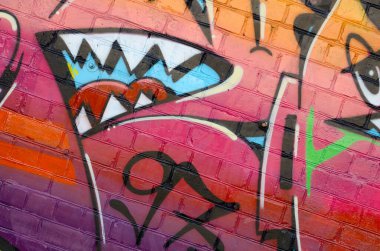 Eski tuğla duvardaki graffiti resimlerinin soyut renkli bir parçası. Yazılmamış mektupların ve renkli lekelerin olduğu sokak sanatı kompozisyonu. Kırmızı renklerde alt kültür arkaplan dokusu