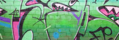 Pembe ve yeşil renklerde eski tuğla duvarlara çizilen graffiti resimlerinin soyut bir parçası. Yazılmamış mektupların ve renkli lekelerin olduğu sokak sanatı kompozisyonu. Alt kültür arka planı
