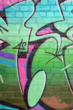 Eski tuğla duvarın üzerine yeşil renkli graffiti resimlerinin soyut bir parçası. Yazılmamış mektupların ve renkli lekelerin olduğu sokak sanatı kompozisyonu. Alt kültür arkaplan dokusu