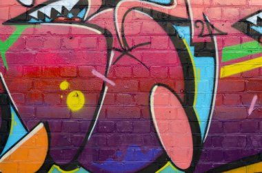 Eski tuğla duvardaki graffiti resimlerinin soyut renkli bir parçası. Yazılmamış mektupların ve renkli lekelerin olduğu sokak sanatı kompozisyonu. Kırmızı renklerde alt kültür arkaplan dokusu