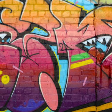 Eski tuğla duvardaki graffiti resimlerinin soyut renkli bir parçası. Yazılmamış mektupların ve renkli lekelerin olduğu sokak sanatı kompozisyonu. Kırmızı renklerde alt kültür arkaplan dokusu