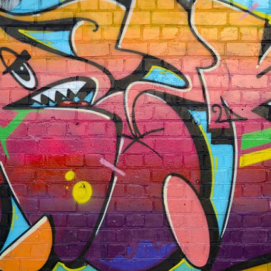 Eski tuğla duvardaki graffiti resimlerinin soyut renkli bir parçası. Vahşi harfler ve renkli lekelerle dolu sokak sanatı kompozisyonu. Sıcak renklerde alt kültür arkaplan dokusu
