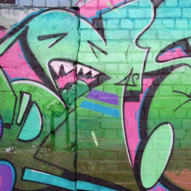 Pembe ve yeşil renklerde eski tuğla duvarlara çizilen graffiti resimlerinin soyut bir parçası. Yazılmamış mektupların ve renkli lekelerin olduğu sokak sanatı kompozisyonu. Alt kültür arka planı