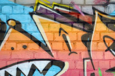 Eski tuğla duvardaki graffiti resimlerinin soyut renkli bir parçası. Vahşi harfler ve renkli lekelerle dolu sokak sanatı kompozisyonu. Sıcak renklerde alt kültür arkaplan dokusu