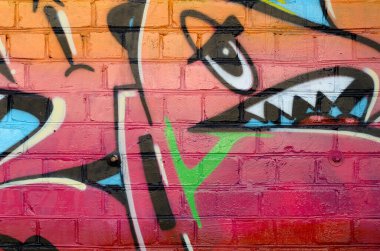 Eski tuğla duvardaki graffiti resimlerinin soyut renkli bir parçası. Yazılmamış mektupların ve renkli lekelerin olduğu sokak sanatı kompozisyonu. Kırmızı renklerde alt kültür arkaplan dokusu