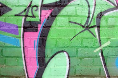 Eski tuğla duvarın üzerine yeşil renkli graffiti resimlerinin soyut bir parçası. Yazılmamış mektupların ve renkli lekelerin olduğu sokak sanatı kompozisyonu. Alt kültür arkaplan dokusu