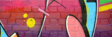 Eski tuğla duvardaki graffiti resimlerinin soyut renkli bir parçası. Vahşi harfler ve renkli lekelerle dolu sokak sanatı kompozisyonu. Sıcak renklerde alt kültür arkaplan dokusu