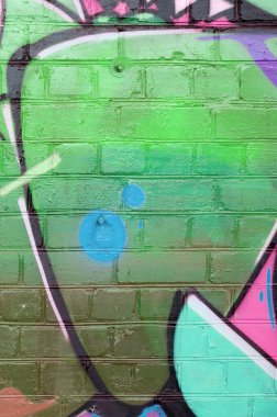 Eski tuğla duvarın üzerine yeşil renkli graffiti resimlerinin soyut bir parçası. Yazılmamış mektupların ve renkli lekelerin olduğu sokak sanatı kompozisyonu. Alt kültür arkaplan dokusu