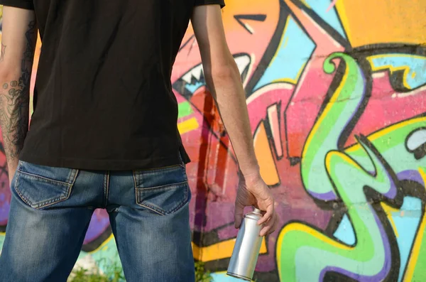 Sırt çantası ve gaz maskesi takan genç grafiti sanatçısı, tuğla duvara pembe tonlarda grafiti yapıyor. Sokak sanatı ve çağdaş boyama süreci. Gençlik alt kültüründe eğlence