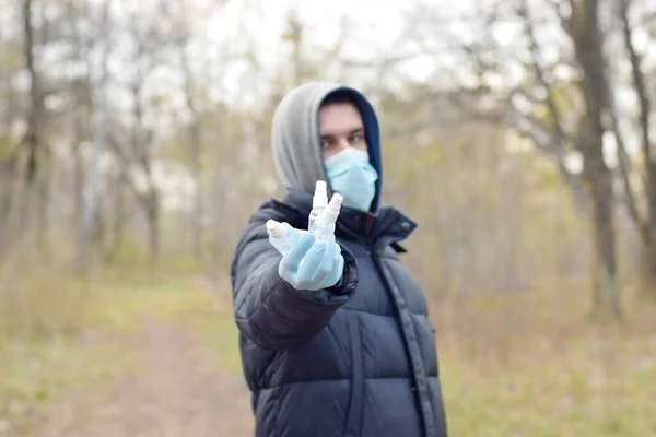 Młody Mężczyzna Masce Ochronnej Pokazuje Butelki Środkiem Dezynfekującym Zewnątrz Wiosennym — Zdjęcie stockowe