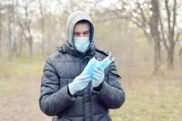 Młody Mężczyzna Masce Ochronnej Pokazuje Maski Ochronne Zewnątrz Wiosennym Drewnie — Zdjęcie stockowe