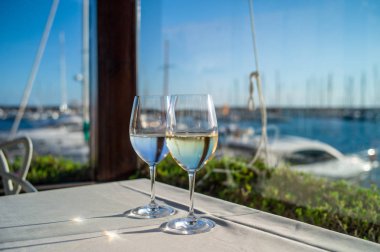 Deniz manzaralı bir restoranda, masada bir kadeh şarap.