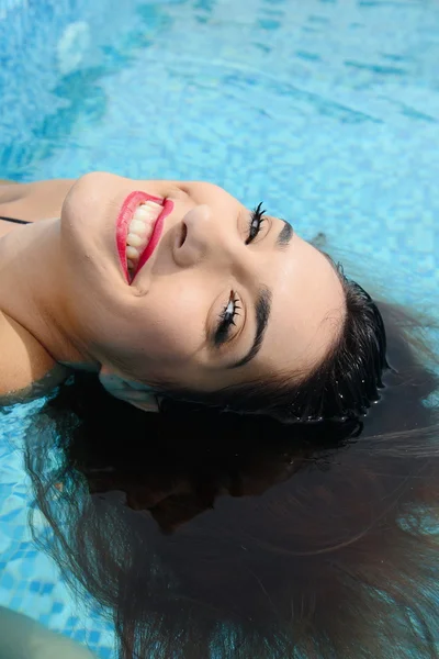 Gyönyörű fiatal nő a víz a medence mellett pihentető — Stock Fotó