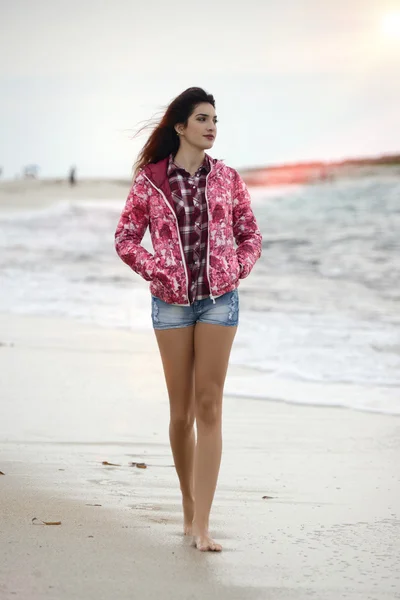 Menina bonita com blusão colorido andando na praia — Fotografia de Stock