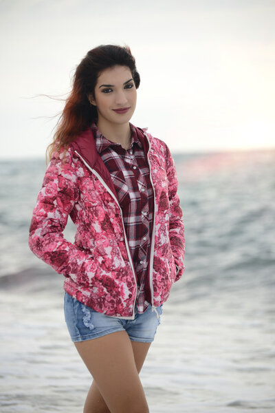 beautiful girl with colorful windbreaker walking on the beach