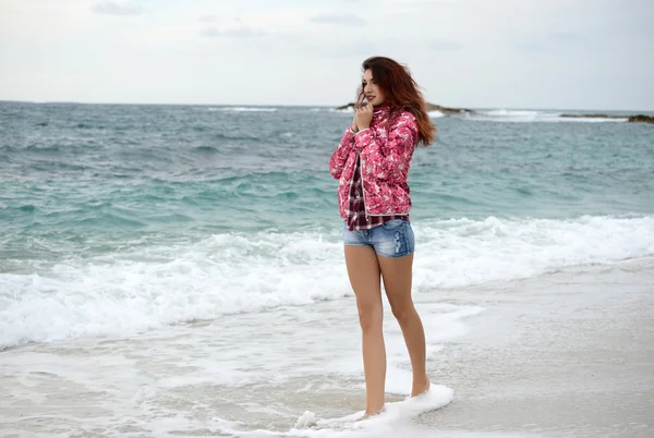 Mooi meisje met kleurrijke windbreaker wandelen op het strand — Stockfoto