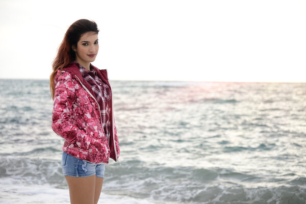 beautiful girl with colorful windbreaker walking on the beach