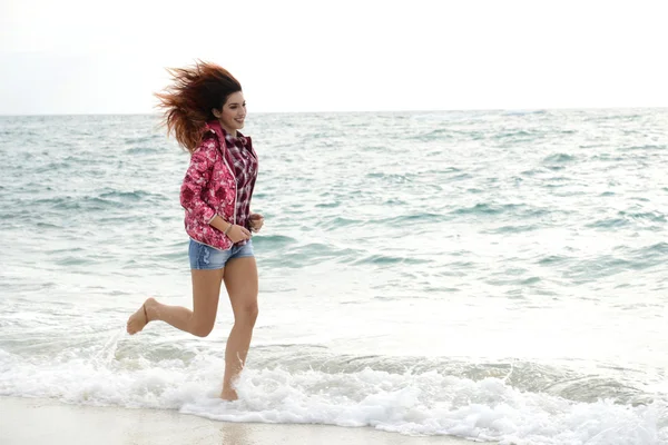 多彩的风衣，运行在海滩上的漂亮女孩 — 图库照片