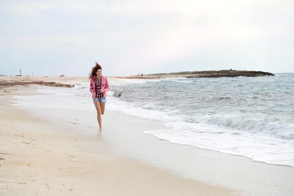 Menina bonita com blusão colorido correndo na praia — Fotografia de Stock