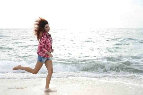 Krásná dívka s barevnými větrovka běžící na pláži — Stock fotografie