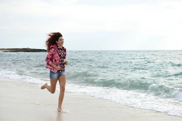 Piękna dziewczyna z kolorowych wiatrówka uruchomiona na plaży — Zdjęcie stockowe