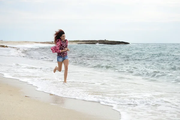Menina bonita com blusão colorido correndo na praia — Fotografia de Stock