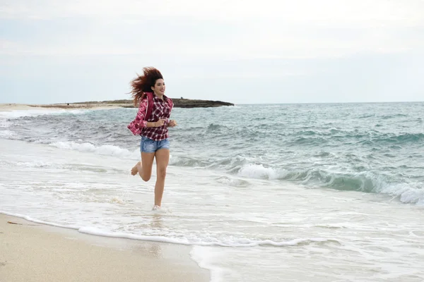 Menina bonita com blusão colorido correndo na praia — Fotografia de Stock