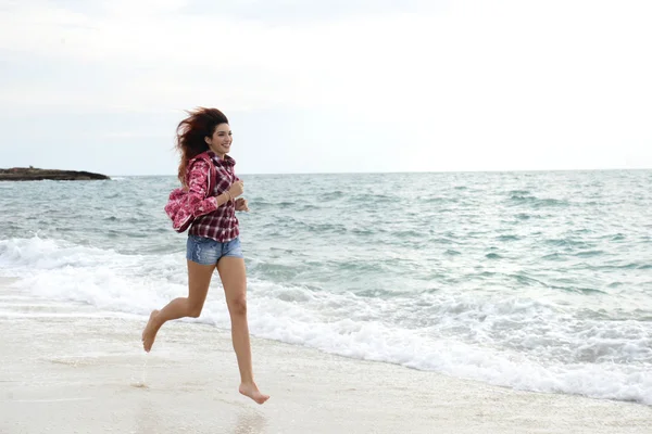 Menina bonita com blusão colorido correndo na praia — Fotografia de Stock