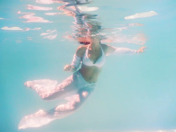 Gyönyörű test úszni a víz alatt fehér ruhás nő — Stock Fotó