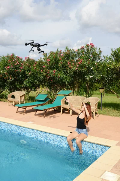 Menina mosca drone com controle remoto pela piscina — Fotografia de Stock