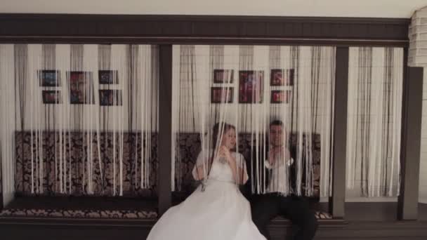 Una giovane coppia, un uomo e una donna che giocano in una stanza con le tende . — Video Stock