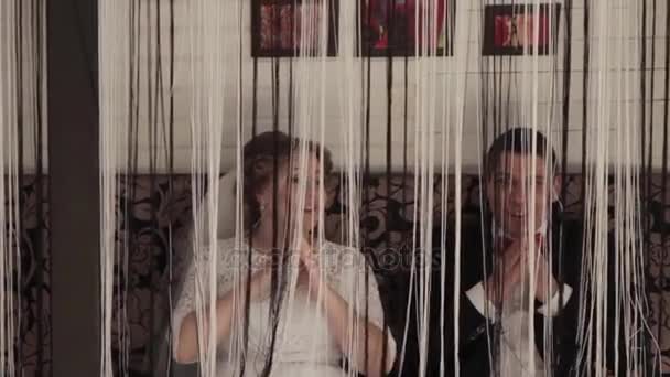 A young couple, a man and a woman fooling around in a room with curtains. — Stock Video