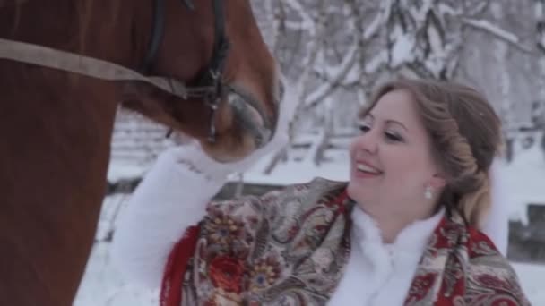 La novia está de pie cerca de un caballo. La novia sonríe. la novia acariciando el caballo . — Vídeos de Stock