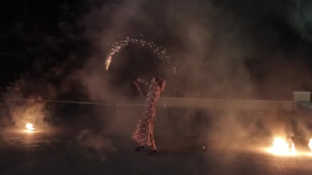 The girl on the ground shows the fire show. The room with sparklers. In full growth. In the evening time. Night. Beautiful, swirling lights. Sparks fly. — Stock Video