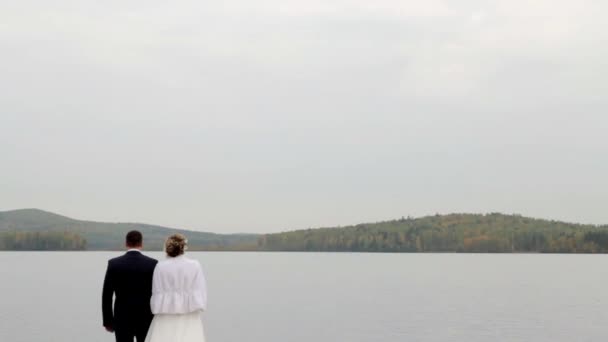 Nevěsta a ženich procházky u jezera, drželi se za ruce. Podzim. — Stock video