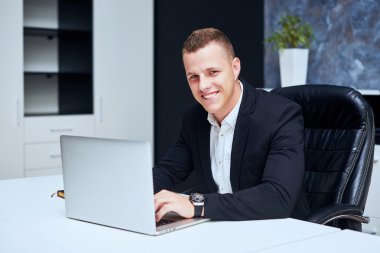 Genç şirket yöneticisi rahat şık bir sandalyede oturuyor