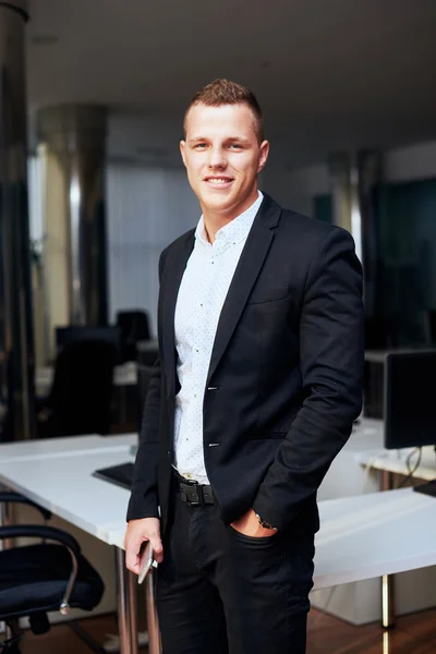 Young corporate executive sitting comfortably in a stylish chair, using a digital tablet, with gentle sunflare through the large windows of a modern office — Stock Photo, Image